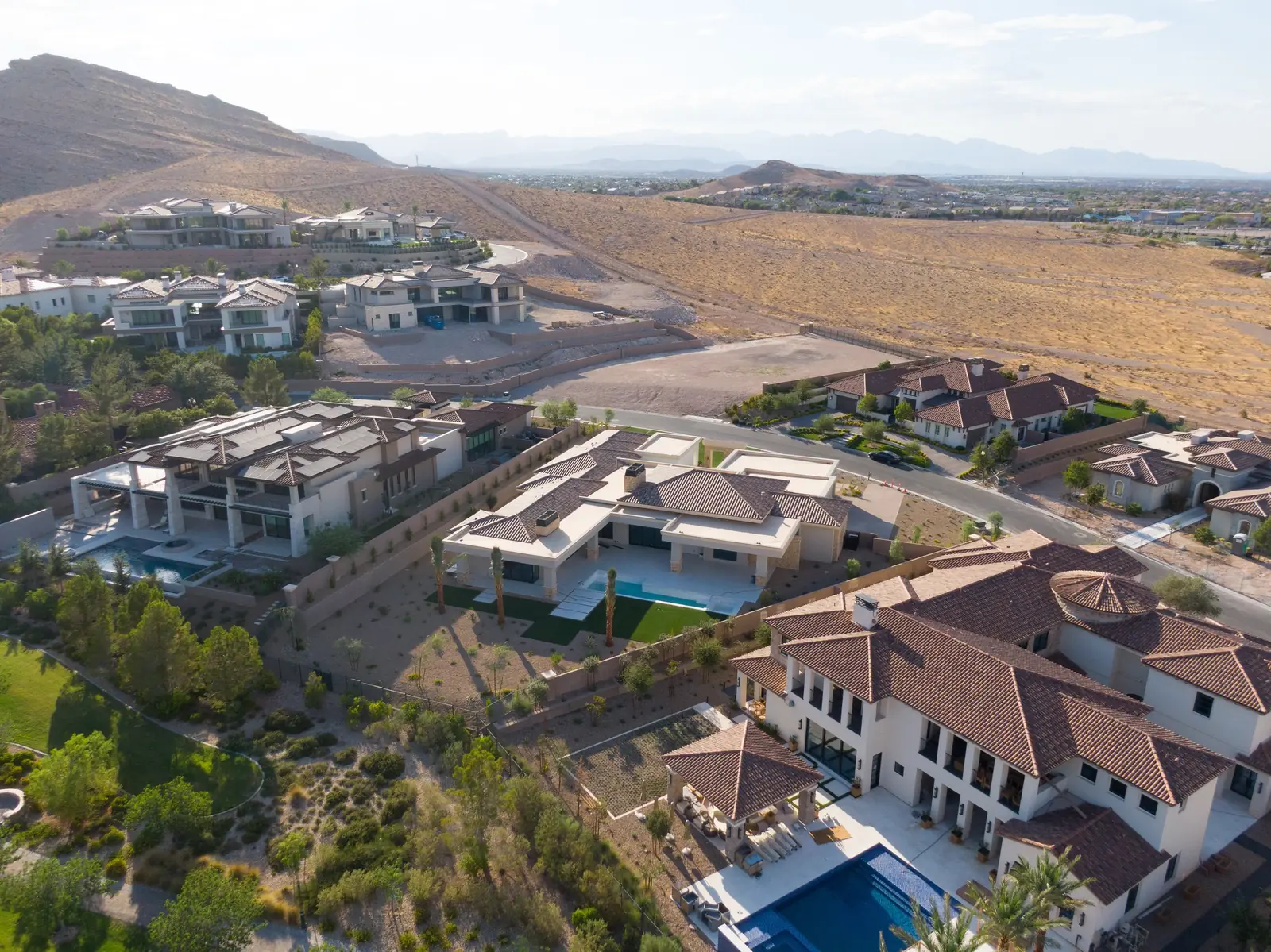 Aerial with the house in the foreground, the greenbelt behind it and the mountains beyond