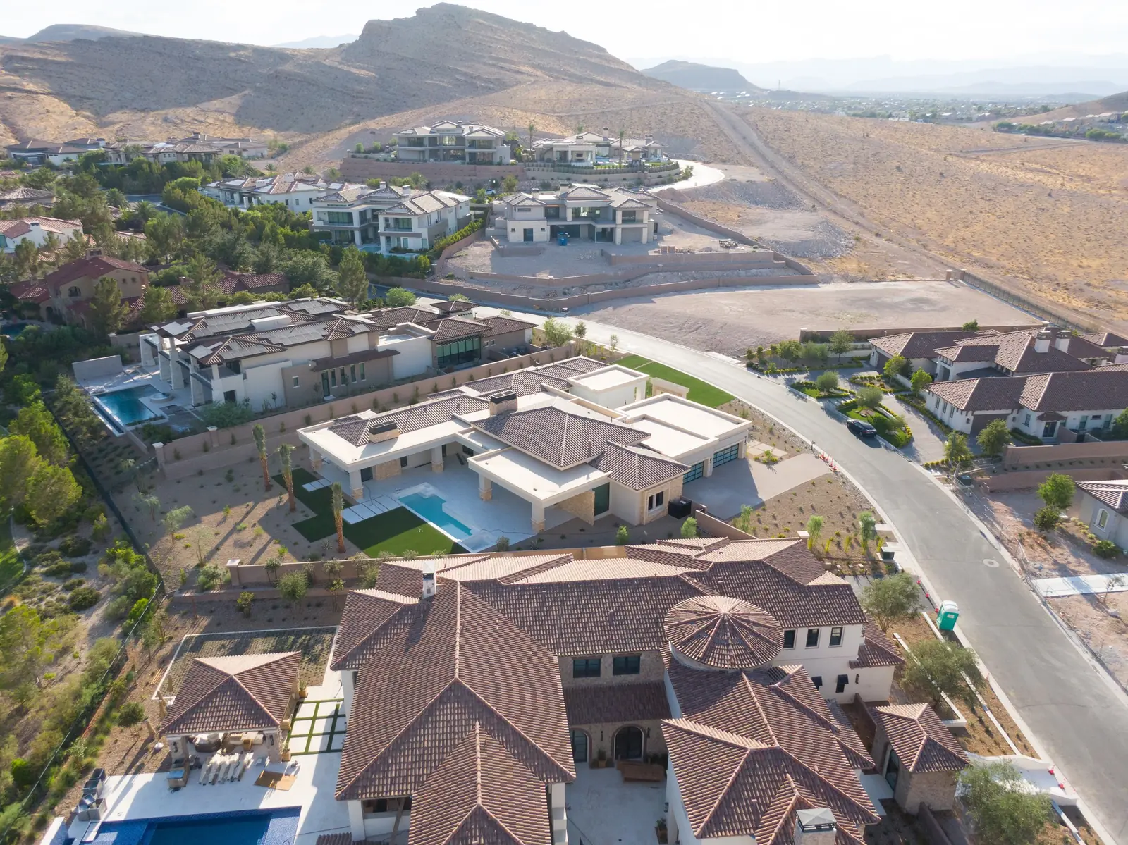 Aerial of the house from above showing the pool and rear yard on one side, the street on the other, and the greenbelt past the rear boundary