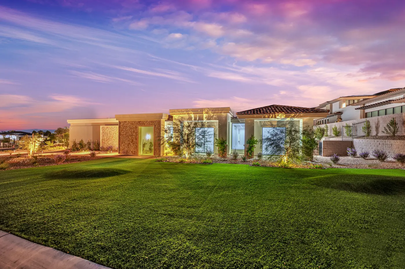 Front lawn at dusk with the house lit behind it