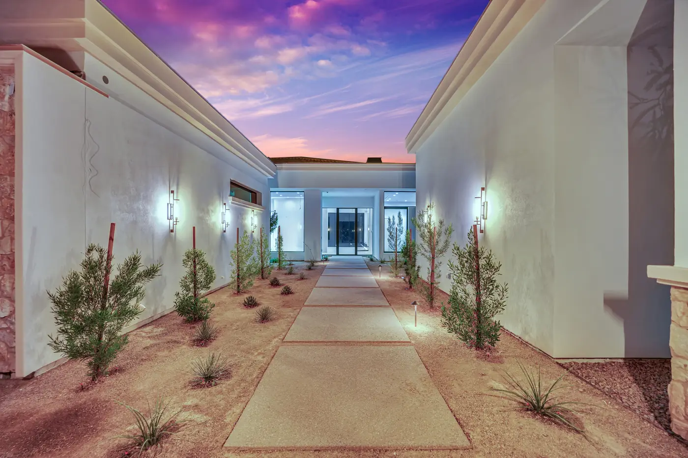 Looking along the lit courtyard to the front door at dusk