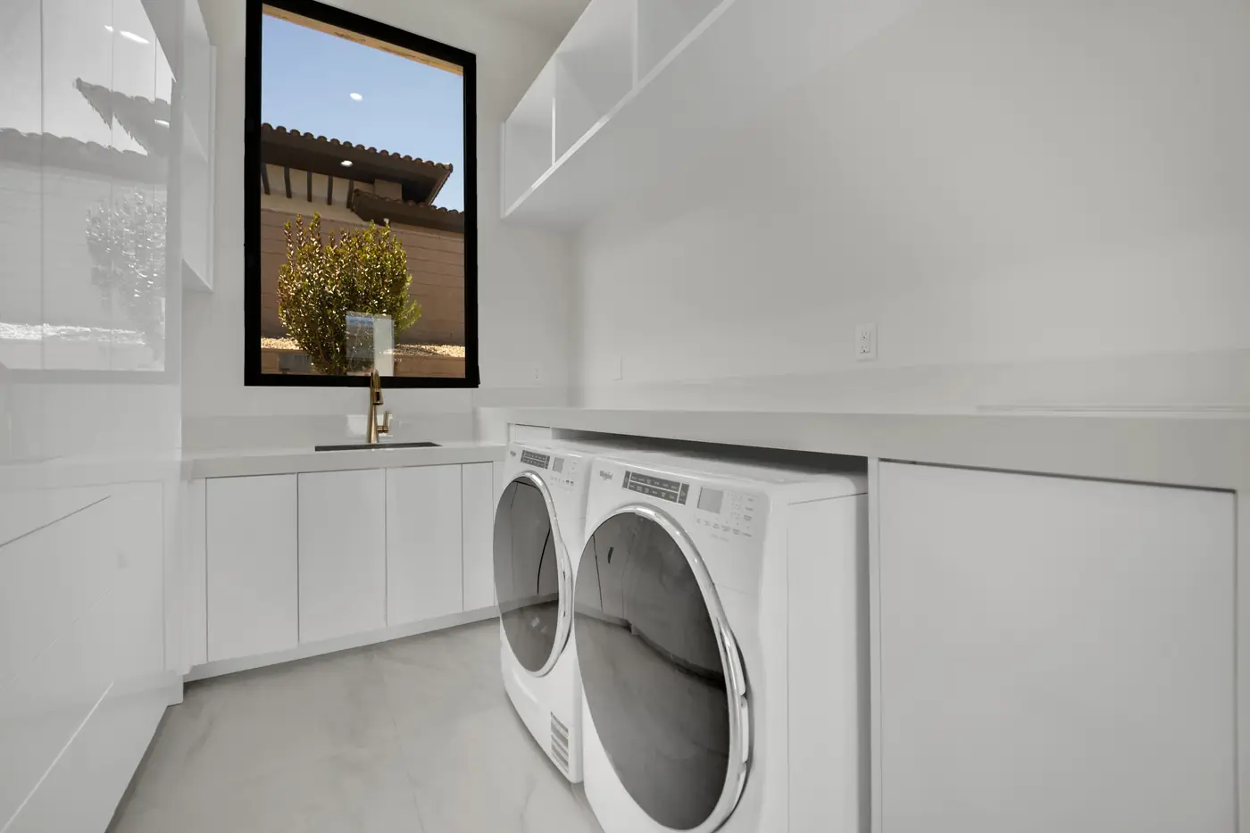Laundry with a washer and dryer under a run of counter and a window above