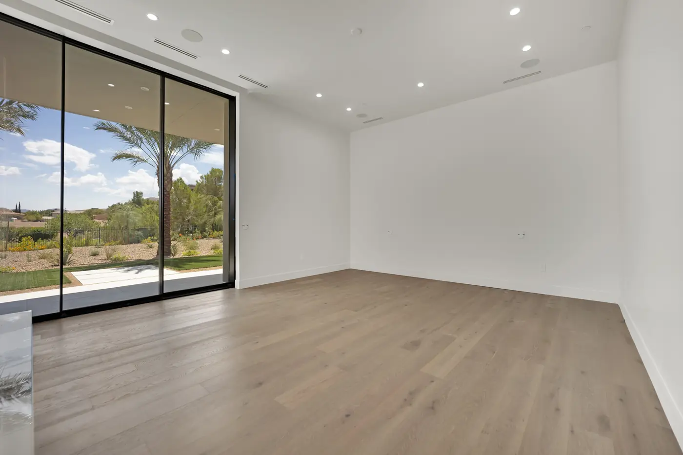 Room with a wood floor and a wall of sliding glass onto the patio