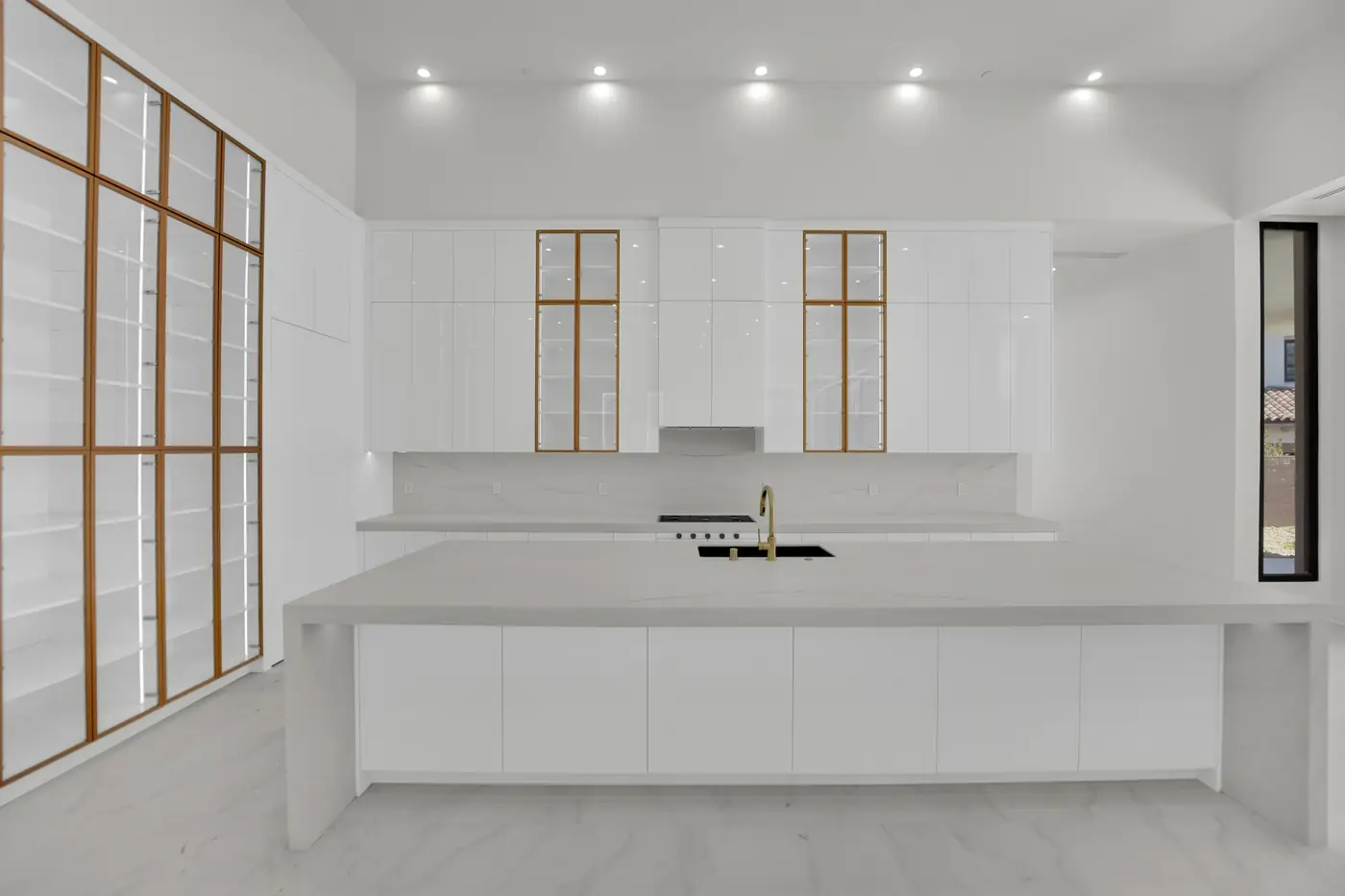 Kitchen with a long island, wood framed glass cabinetry and a run of counter behind