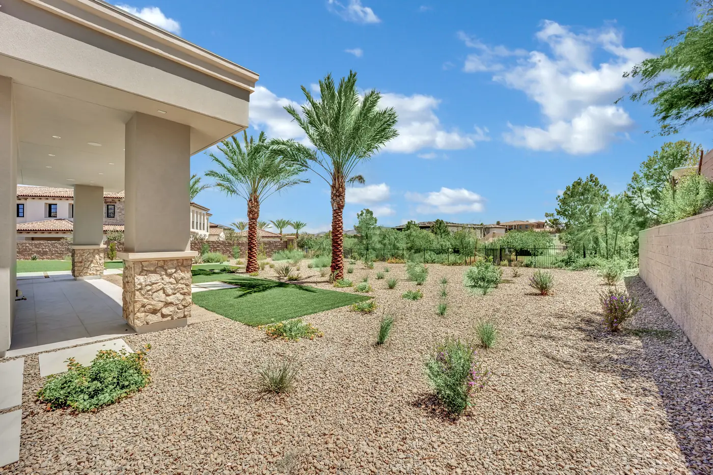 Covered patio seen from the yard with palms and desert planting in front of it