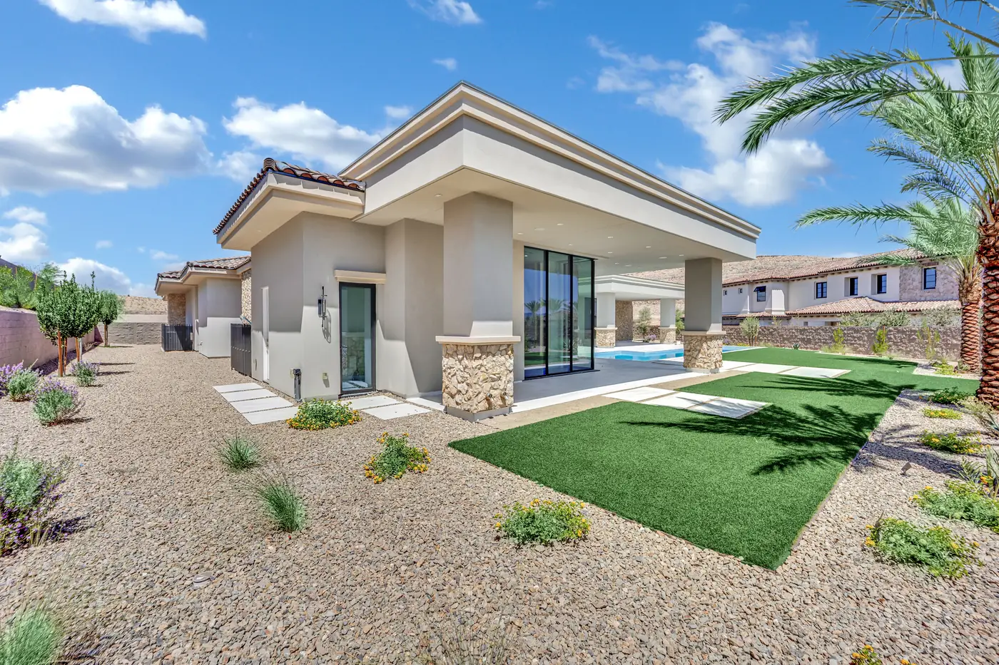 Rear elevation of the house from the lawn, with the covered patio, pool and palms