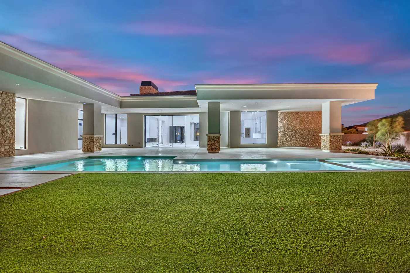 Rear elevation at dusk with the patio lit and the pool glowing