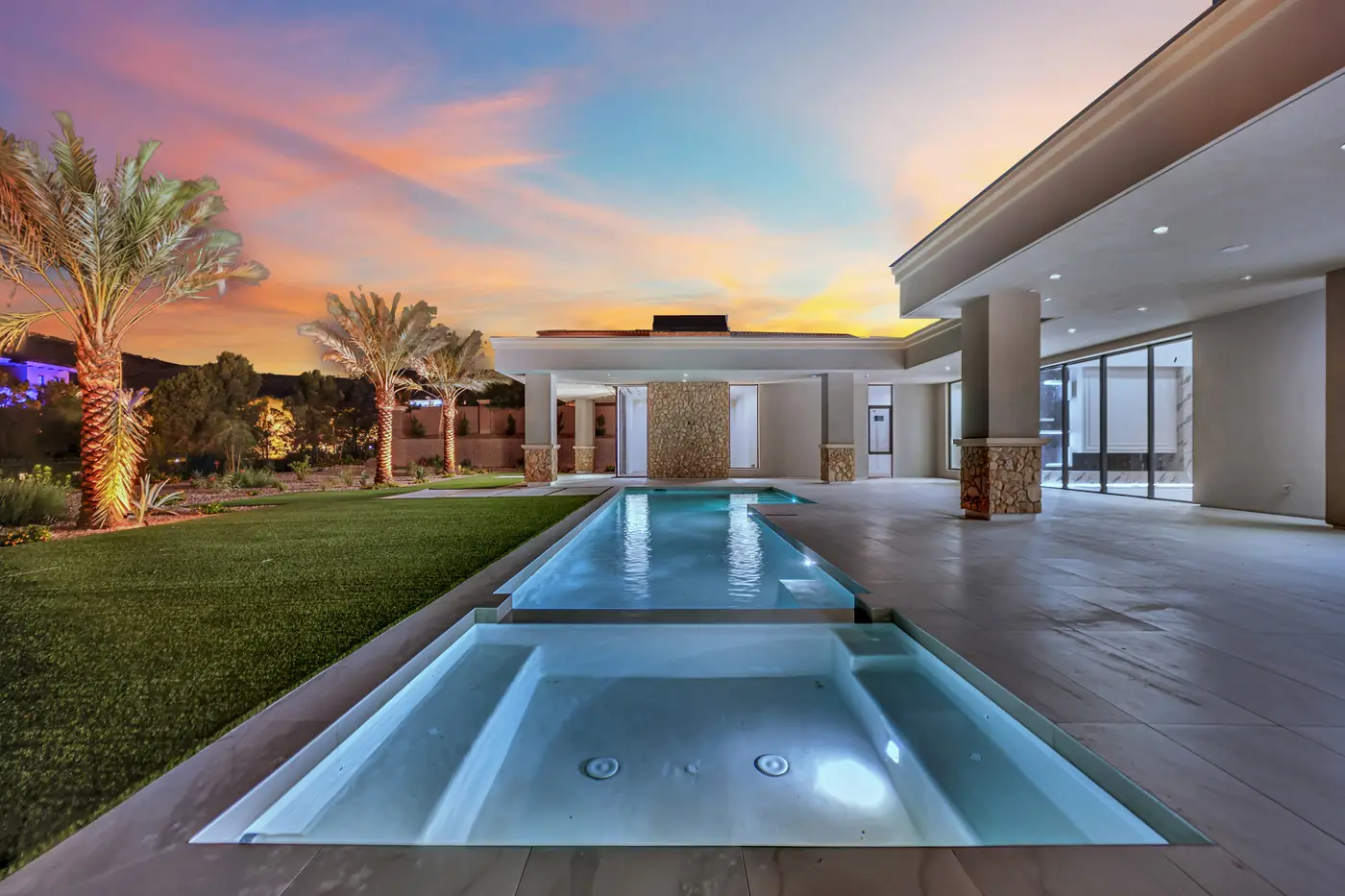 Pool and palms at dusk with the patio lit behind